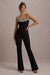 Amadi | Schwarzer Jumpsuit mit Verzierungen, Trägern und ausgestelltem Bein.