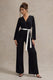 Ruba | Schwarzer, maßgeschneiderter Jumpsuit mit tiefem Ausschnitt und Bindegürtel.