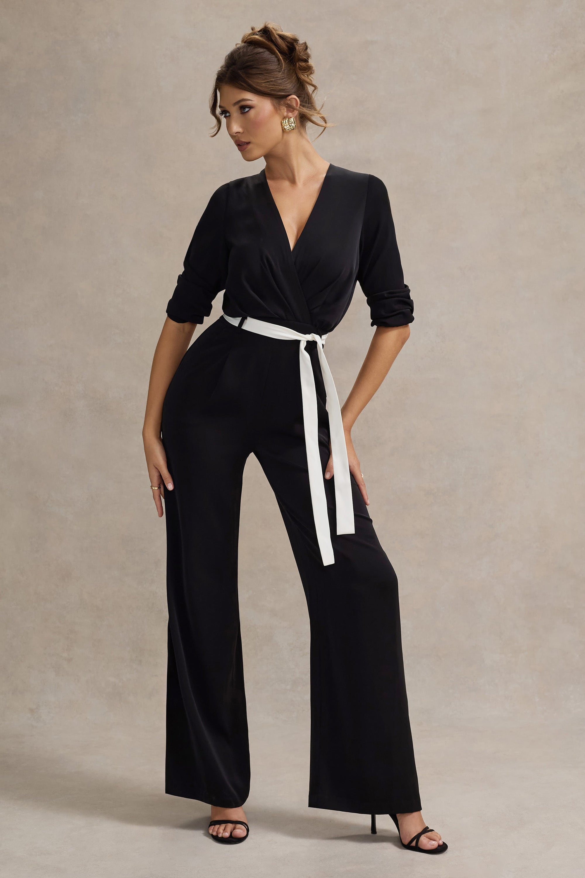 Ruba | Schwarzer, maßgeschneiderter Jumpsuit mit tiefem Ausschnitt und Bindegürtel.